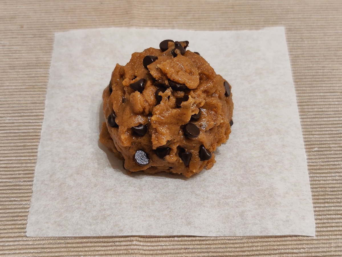 Una pallina di impasto con le gocce di cioccolato, sulla carta forno